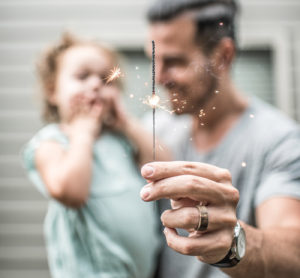 A man and child holding sparklers in their hands.